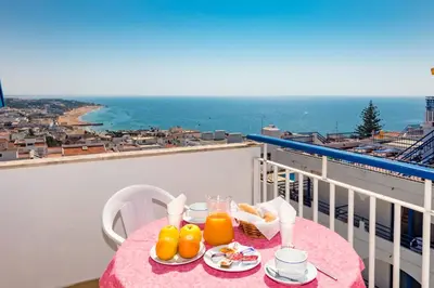 a pink table with orange juice and food on a balcony at Hotel Mar A Vista in Albufeira
