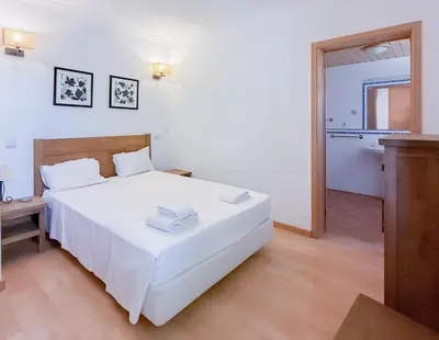 a bedroom with a white bed and a bathroom at Oleandro Country Club in Albufeira