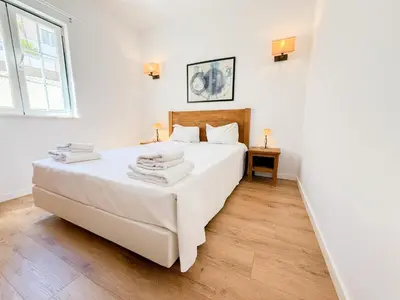 a white bedroom with a large bed and a window at Oleandro Country Club in Albufeira