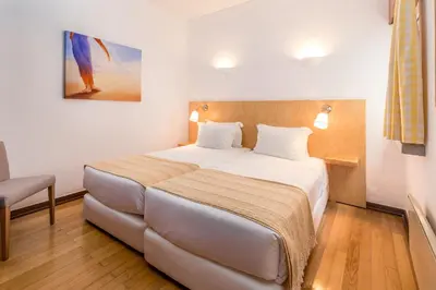 a hotel room with a large bed and a chair at Apartamentos Turisticos Pinhal Da Marina in Vilamoura