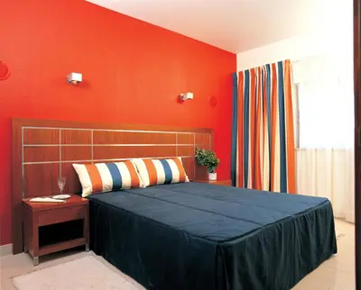 a bedroom with a bed and a red wall at Hotel Apartamento Balaia Atlantico in Albufeira