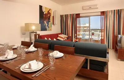 a dining room with a table and a couch at Hotel Apartamento Balaia Atlantico in Albufeira