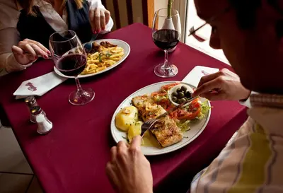 a group of people sitting at a table with plates of food at Hospedaria Frangaria in Faro
