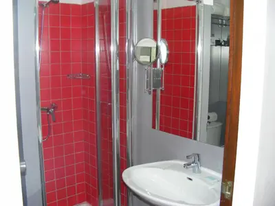 a bathroom with a sink and a shower with red tiles at Rocamar Exclusive Hotel & Spa - Adults Only in Albufeira