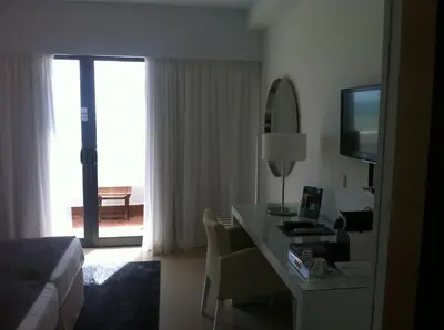 a hotel room with a desk and a bed and a television at Rocamar Exclusive Hotel & Spa - Adults Only in Albufeira