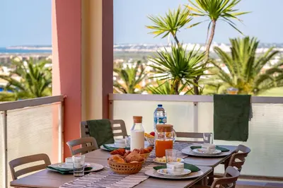 a wooden table with food on a balcony with palm trees at Parque Monte Verde in Albufeira