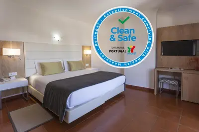 a bedroom with a bed and a sign that says clean and safe at Best Western Hotel Dom Bernardo in Faro