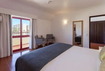 a bedroom with a bed and a table with chairs at Best Western Hotel Dom Bernardo in Faro