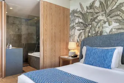 a bedroom with a bed and a bathroom with a tub at Domes Lake Algarve, Autograph Collection in Vilamoura