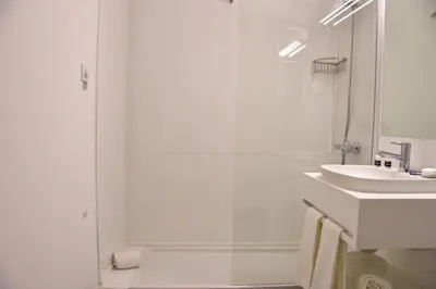 a white bathroom with a shower and a sink at Hotel Sol Algarve by Kavia in Faro