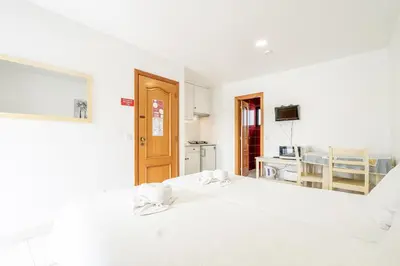 a white room with a bed and a kitchen at Apartamentos Vale de Carros by Umbral in Albufeira