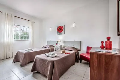 a room with two beds and a red couch at Villa Torcato in Albufeira