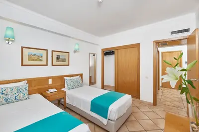 a hotel room with two beds and a table at Oceanus Aparthotel in Albufeira