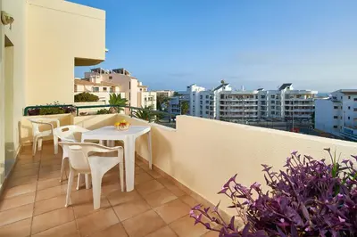 a balcony with tables and chairs on a building at Oceanus Aparthotel in Albufeira