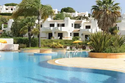 a swimming pool in front of a large white house at Clube Albufeira Garden Village in Albufeira