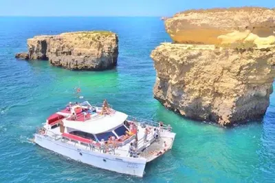 a boat in the water near two large rocks at 60m2 Lovely traditional apartment in Clube Albufeira in Albufeira