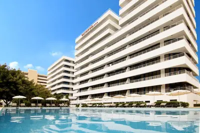 a large white building with umbrellas and a swimming pool at The Navigator - Olympus Marina in Vilamoura
