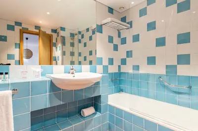 a bathroom with blue and white tiled walls and a sink at The Patio Suite Hotel in Albufeira