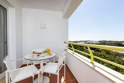 a dining room and living room with a table and chairs at The Patio Suite Hotel in Albufeira