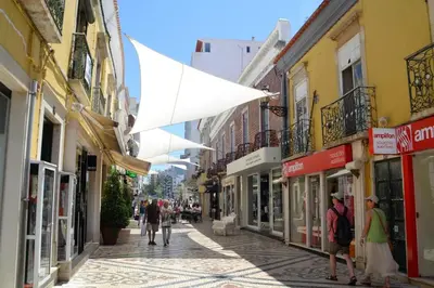 a street with people walking down a street with buildings at Sweet Dream House in Faro