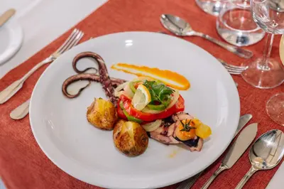 a plate of food with meat and fruit on a table at Grand Muthu Oura View Beach Club in Albufeira