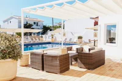 a patio with a pool and chairs and a white umbrella at Vila Channa - Adults Only in Albufeira