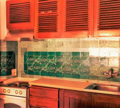 a kitchen with red cabinets and green tiles on the wall at Albufeira Jardim by Umbral in Albufeira