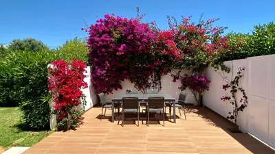 a table and chairs in a garden with pink flowers at Galo by Check-in Portugal in Albufeira