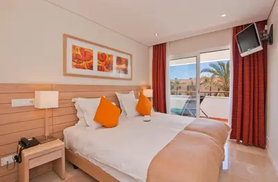 a bedroom with a bed with orange pillows and a window at As Cascatas Golf Resort & Spa in Vilamoura