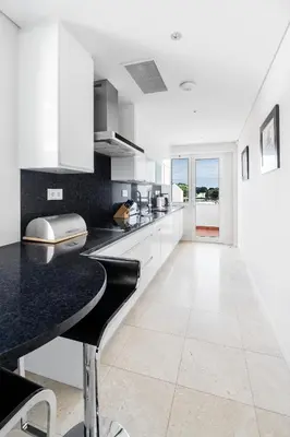 a kitchen with white cabinets and a black counter top at As Cascatas Golf Resort & Spa in Vilamoura