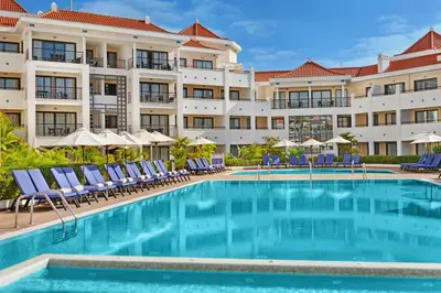 a pool in front of a hotel with chairs and umbrellas at As Cascatas Golf Resort & Spa in Vilamoura
