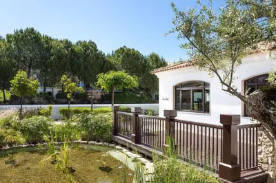 a garden with a fence and a pond at Pine Cliffs Residence, a Luxury Collection Resort, Algarve in Albufeira