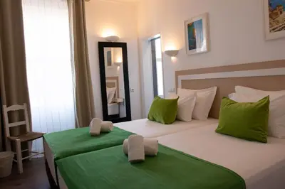 a bedroom with two beds with green sheets and a mirror at Albufeira Beach Hotel by Kavia in Albufeira