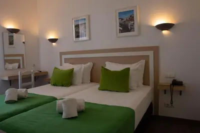 a bedroom with two beds with green pillows at Albufeira Beach Hotel by Kavia in Albufeira