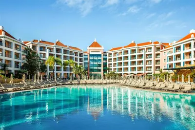 a pool at a resort with chairs and buildings at Hilton Vilamoura in Vilamoura