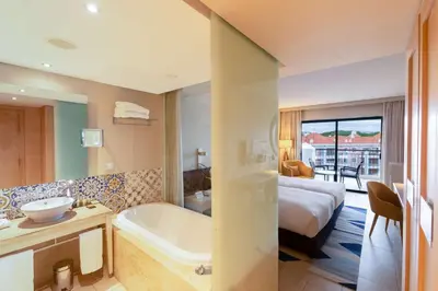 a bedroom with a large white bed and a chair at Hilton Vilamoura in Vilamoura