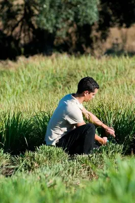 a man sitting in the grass in a field at Quinta Do Mel in Albufeira