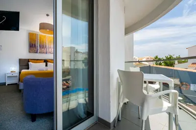 a room with a balcony with a bed and a table and chairs at KR Hotels - Albufeira Lounge in Albufeira