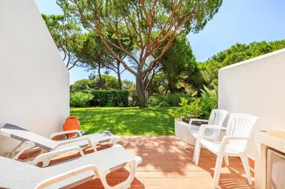 a patio with white chairs and a tree at Victory Village Club 9F in Quinta do Lago