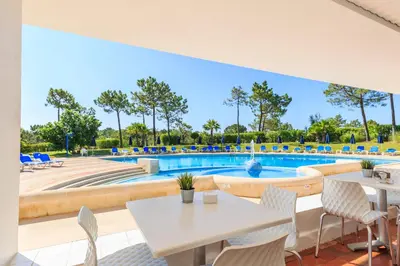 a patio with a table and chairs and a swimming pool at Victory Village Club 9F in Quinta do Lago