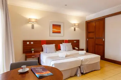 a hotel room with two beds and a table at Hotel Praia Sol in Quarteira