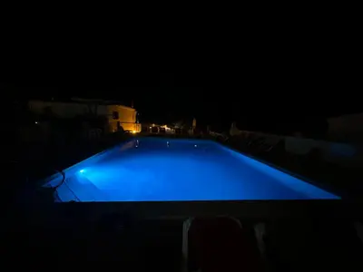 a large blue swimming pool at night at Apartamentos Do Parque in Albufeira