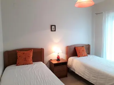 a bedroom with two beds and a table with a lamp at T2 Tahíti - Terraço, Familiar, Garagem, Wifi in Quarteira