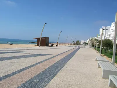 a street with benches and a beach with buildings at Varandas de Carteia G/F in Quarteira
