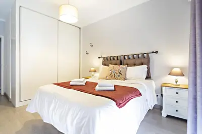 a bedroom with a large white bed with two towels on it at Apartamento Gulbenkian in Faro