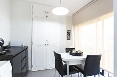 a kitchen with a white table and black chairs at Apartamento Gulbenkian in Faro