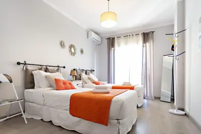 a living room with a white couch and an orange blanket at Apartamento Gulbenkian in Faro