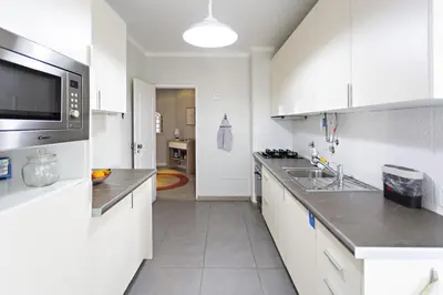 a white kitchen with a sink and a microwave at Apartamento Gulbenkian in Faro