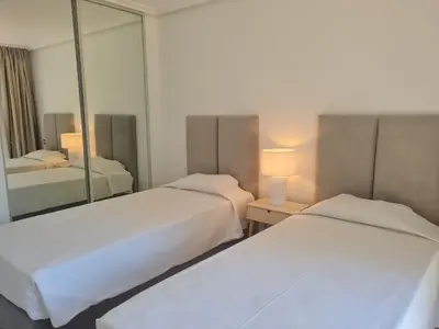 a hotel room with two beds and a mirror at Apartamento Falésia by Garvetur in Albufeira