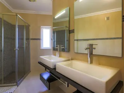 a bathroom with two sinks and a shower and a mirror at Luxury Holiday Villa Alegria Galé Beach, Albufeira in Albufeira